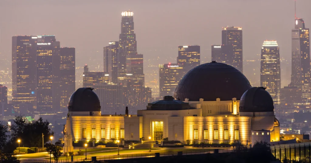 Griffith Observatory lit up at dusk with the Los Angeles skyline behind it