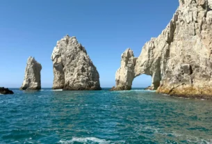 Boat sailing near El Arco rock arch with sea lions at Lover's Beach