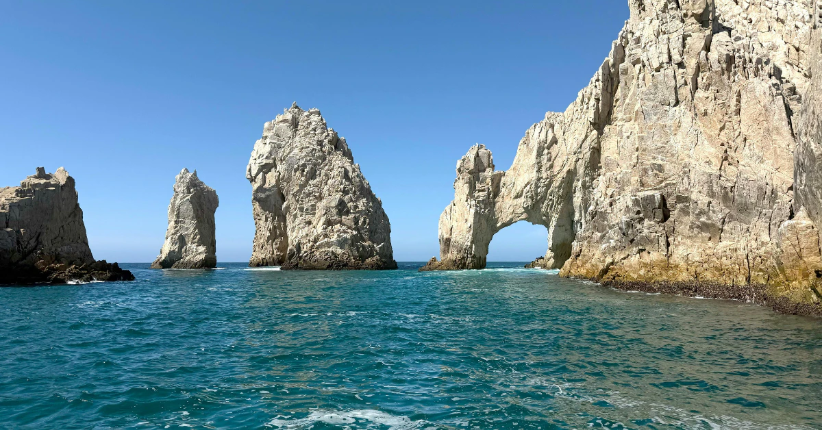 Boat sailing near El Arco rock arch with sea lions at Lover's Beach