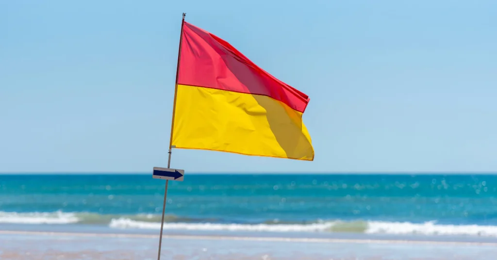 Colored beach safety flags showing swimming conditions at Medano Beach