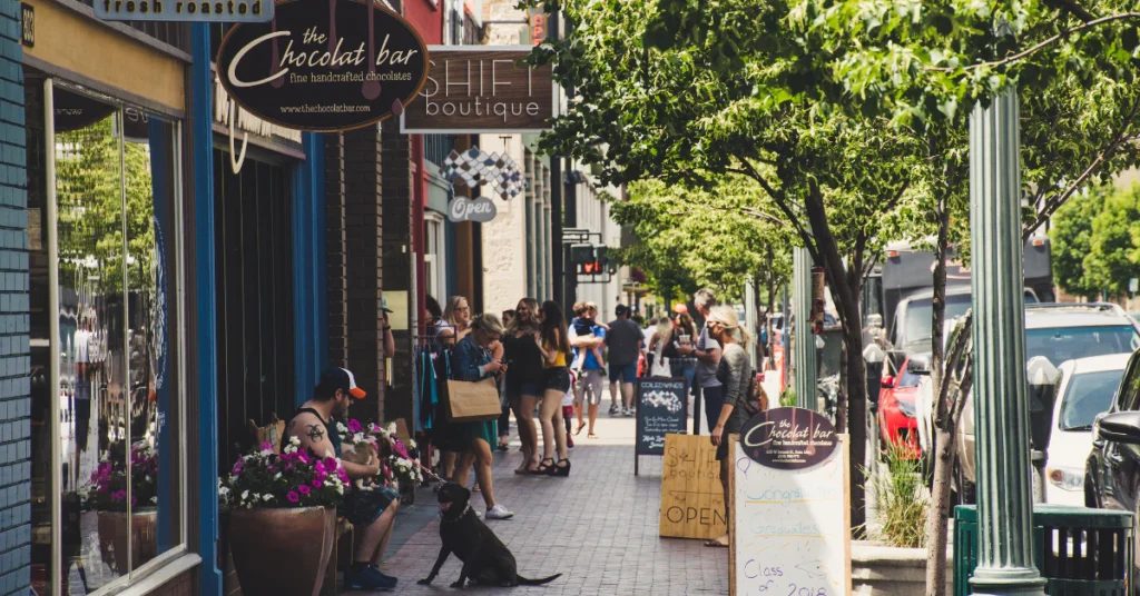 Pedestrians walking through charming town street with shops