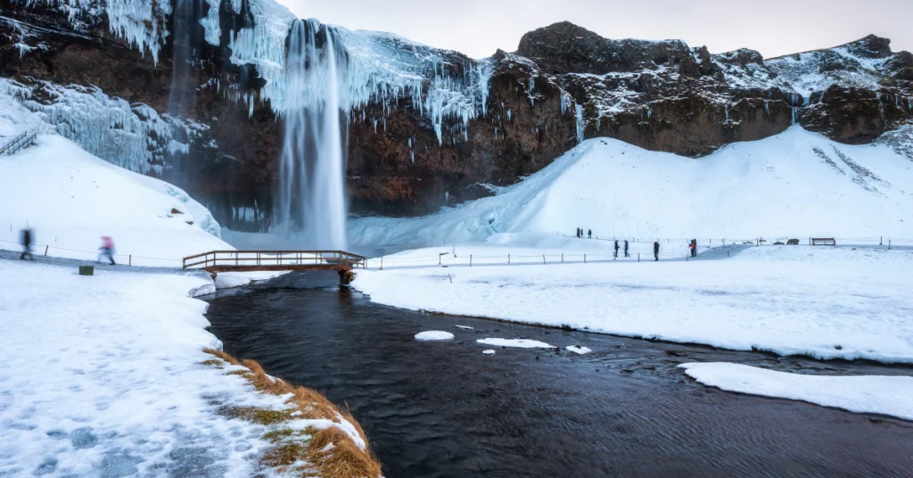 Snow-covered Icelandic waterfall in winter with icy rocks