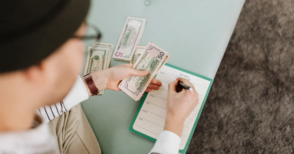 Person counting money and writing in a notebook to plan a travel budget