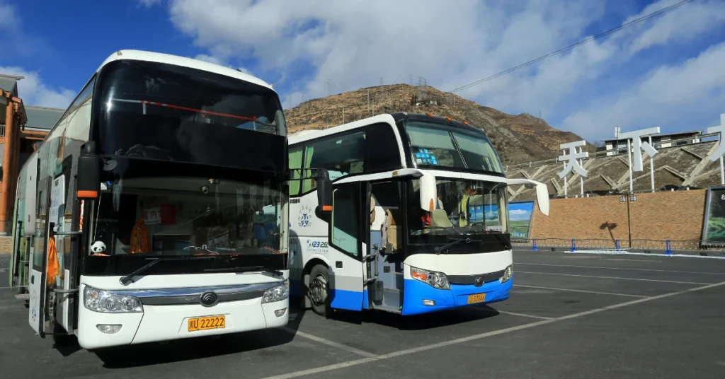 Two city buses parked on a Kyoto street with mountains in the background