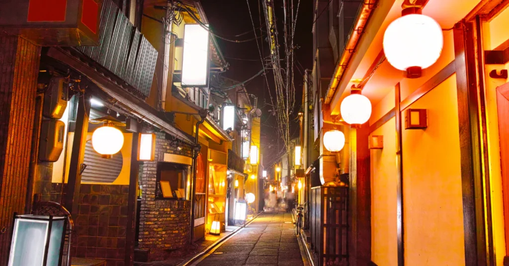 Glowing paper lanterns along a narrow Kyoto alley lined with wooden restaurants at night