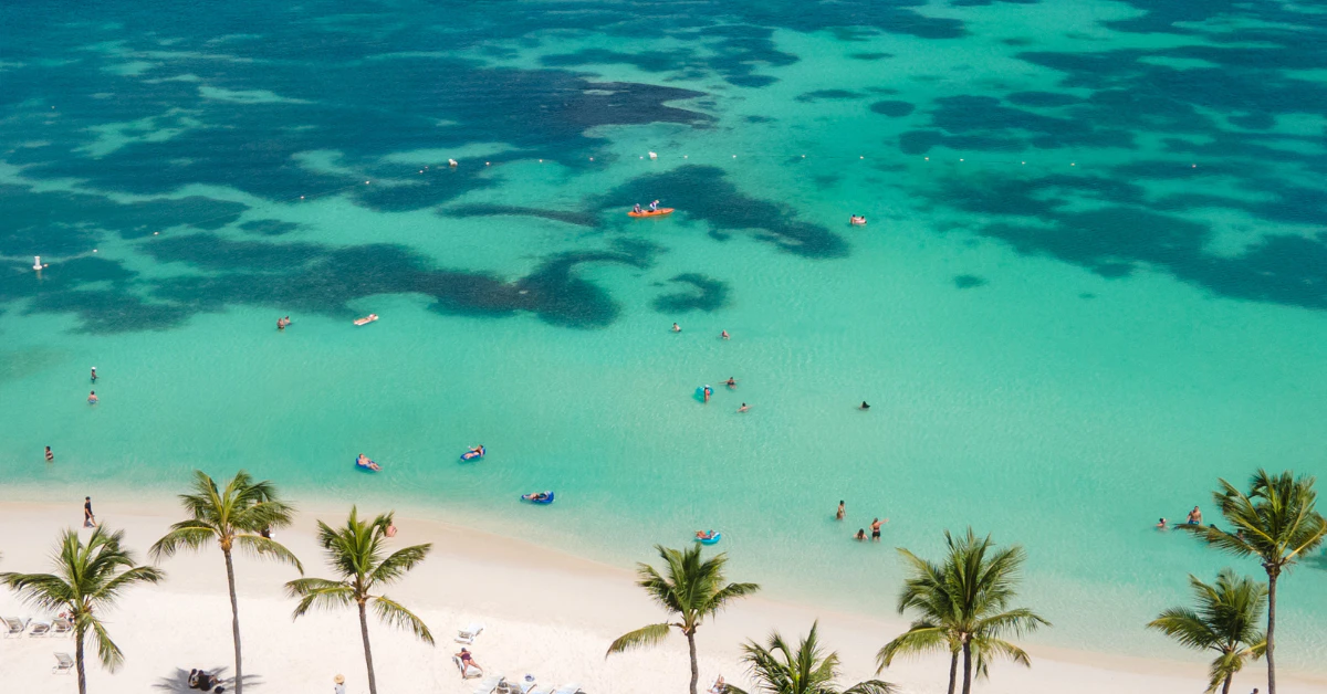 Aerial view of a tropical beach with palm trees, white sand and turquoise Caribbean water