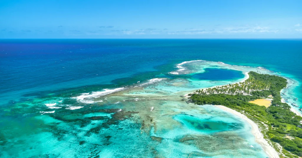 Aerial view of a tropical island with turquoise lagoon and reef surrounded by blue sea