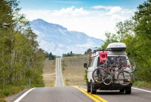 Car with bikes on the back driving on a scenic mountain road