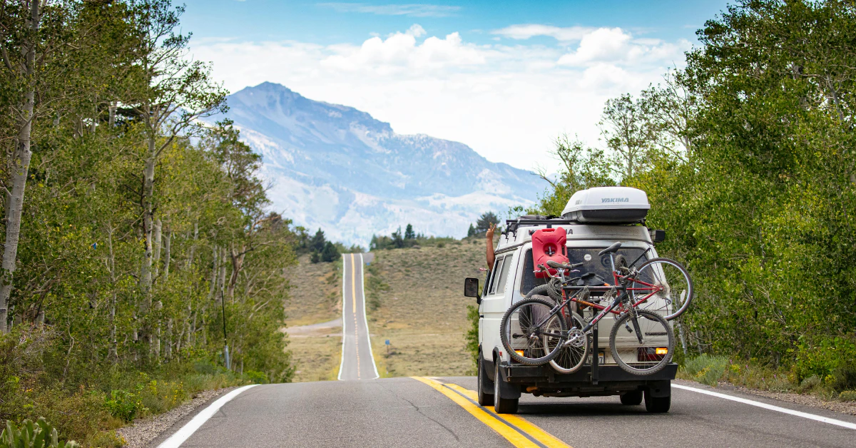 Car with bikes on the back driving on a scenic mountain road