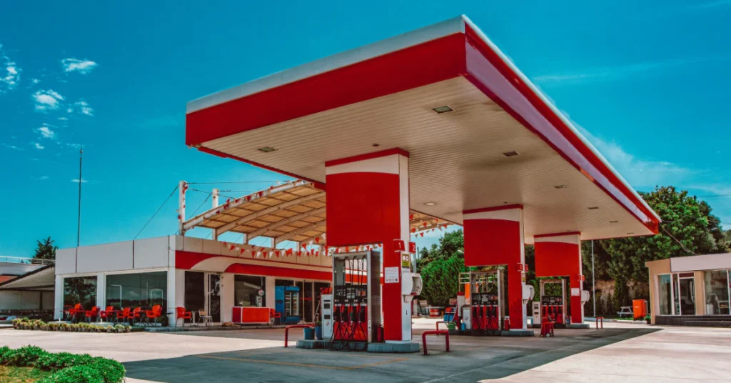 Red and white gas station with fuel pumps under a blue sky
