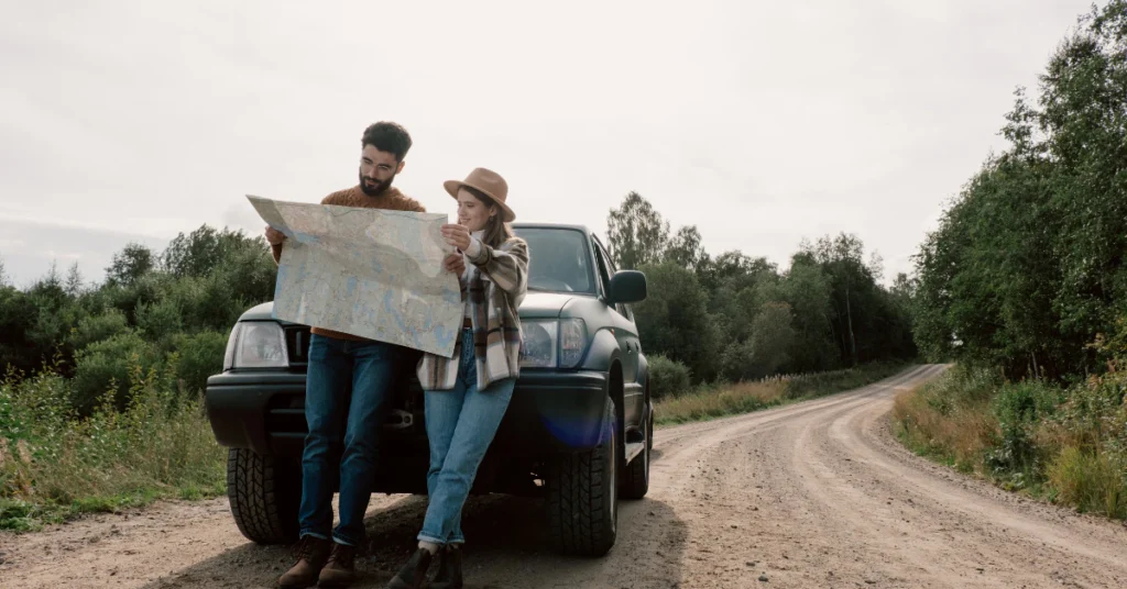 Couple standing by a car reading a map on a scenic roadside