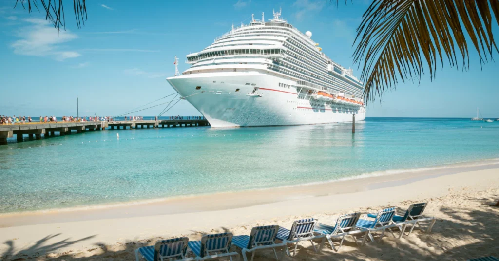 Cruise ship docked beside a pier near a sandy tropical shore