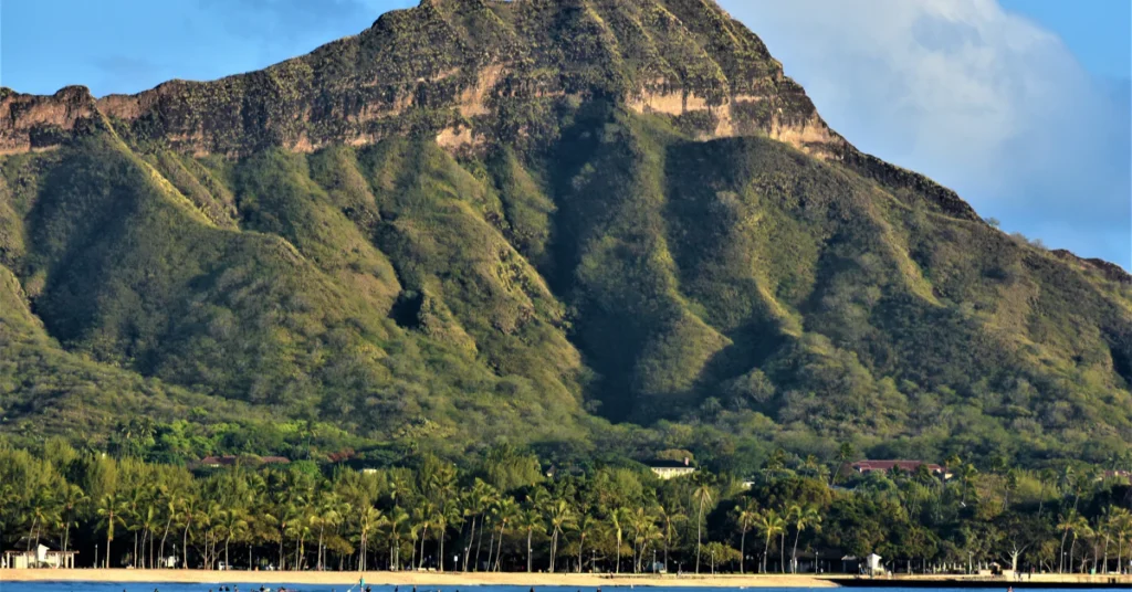Green slopes of Diamond Head crater rising above the coast, a hiking spot in Honolulu that needs a reservation