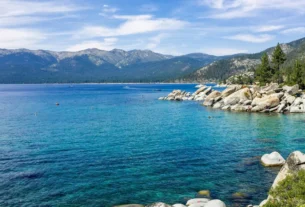 Rocky shoreline and clear blue water with mountains, things to do in Lake Tahoe