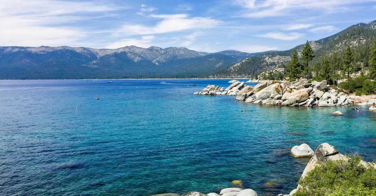 Rocky shoreline and clear blue water with mountains, things to do in Lake Tahoe