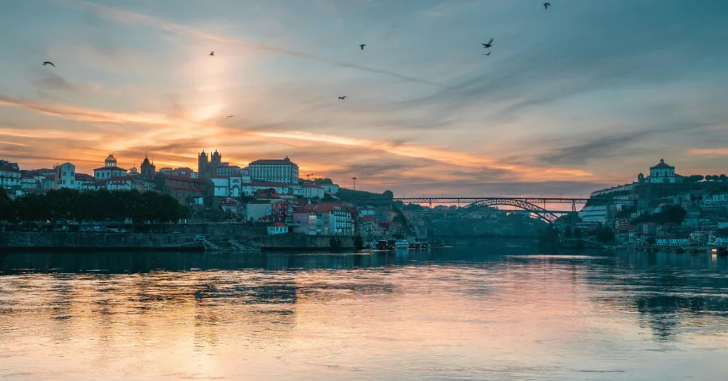Sunset glowing over a calm river with the city skyline in the distance