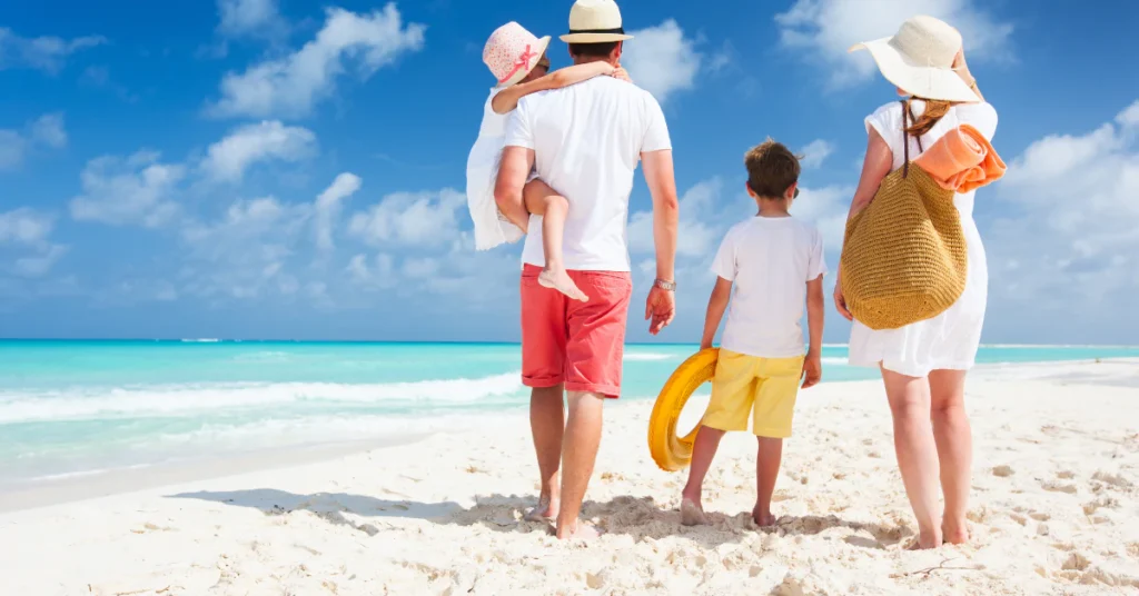 Family with two kids walking along a sandy tropical beach
