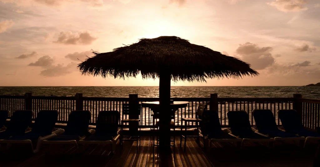 Thatched beach umbrella and lounge chairs at sunset in St. Lucia
