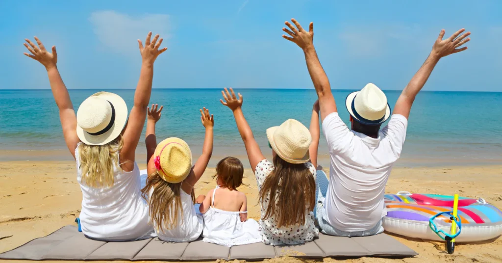 Family with arms raised cheering together on a sunny beach