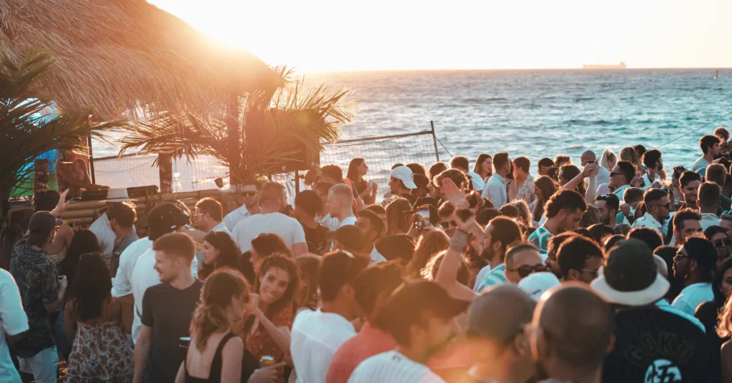 Crowd of people gathered at a beach party at sunset