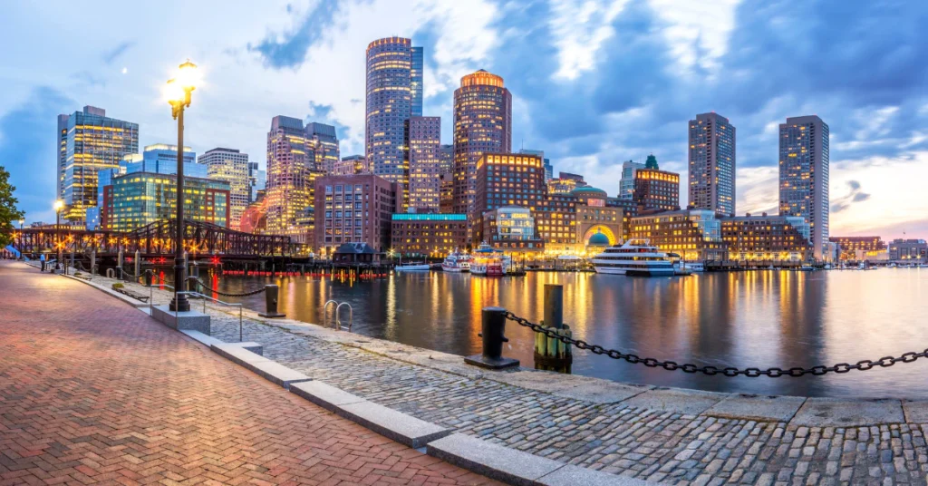 Boston Harbor waterfront with city skyline and boats at sunset