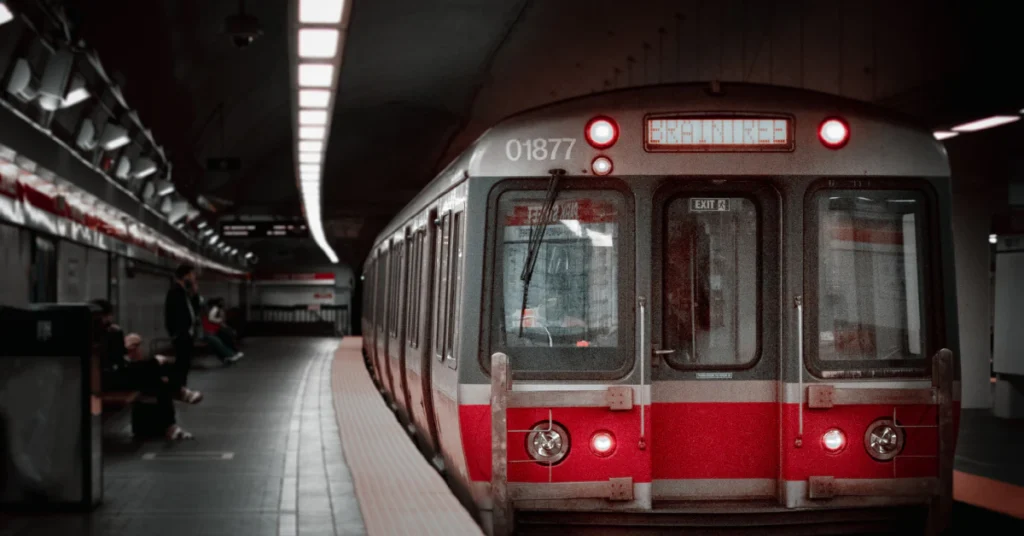 Red subway train arriving at an underground station platform in Boston