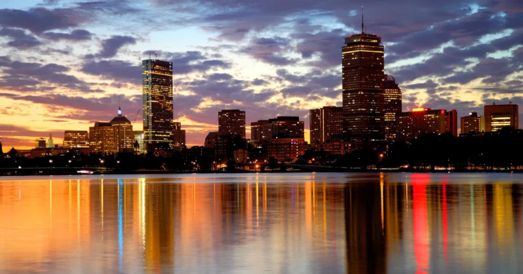Boston city skyline at twilight reflected in the river with a colorful sunset sky